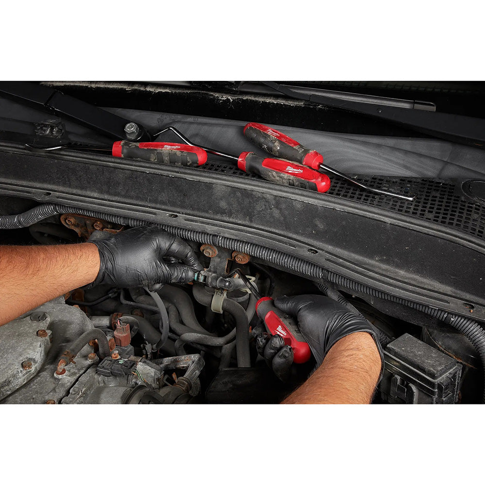 Person working on a car engine with tools, wearing black gloves.