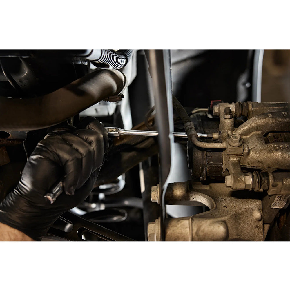 Person working on a mechanical component with tools in a workshop setting