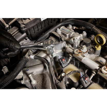 Close-up of a car engine with a wrench being used on mechanical parts.