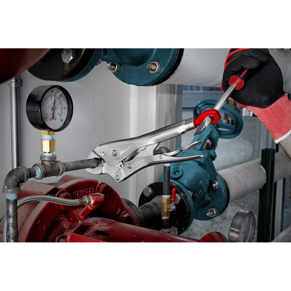 Close-up of a gloved hand using a tool on mechanical equipment with gauges.