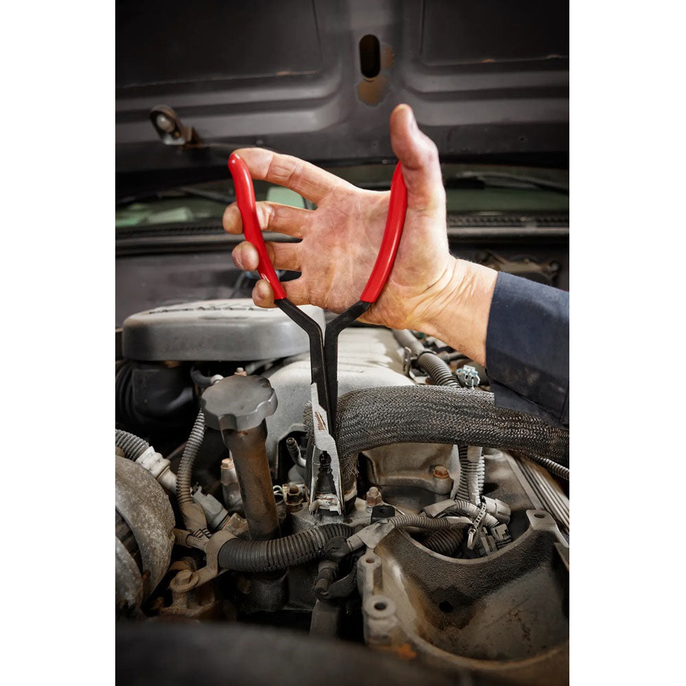 Hand using red pliers on a car engine