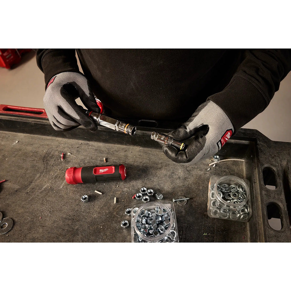 Person using a tool on a workbench with various hardware items.