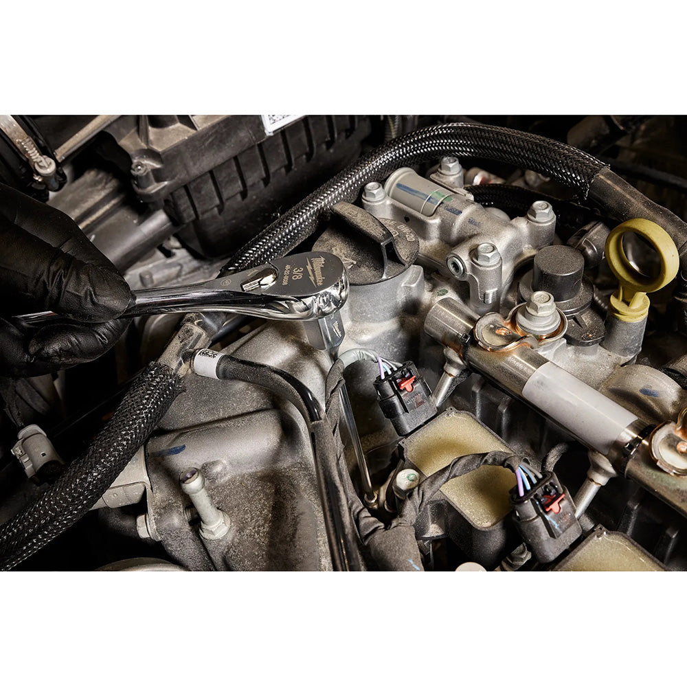 Close-up of a car engine with a wrench being used on mechanical parts.