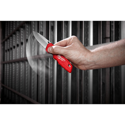 Hand holding a red pocket knife against a blurred background