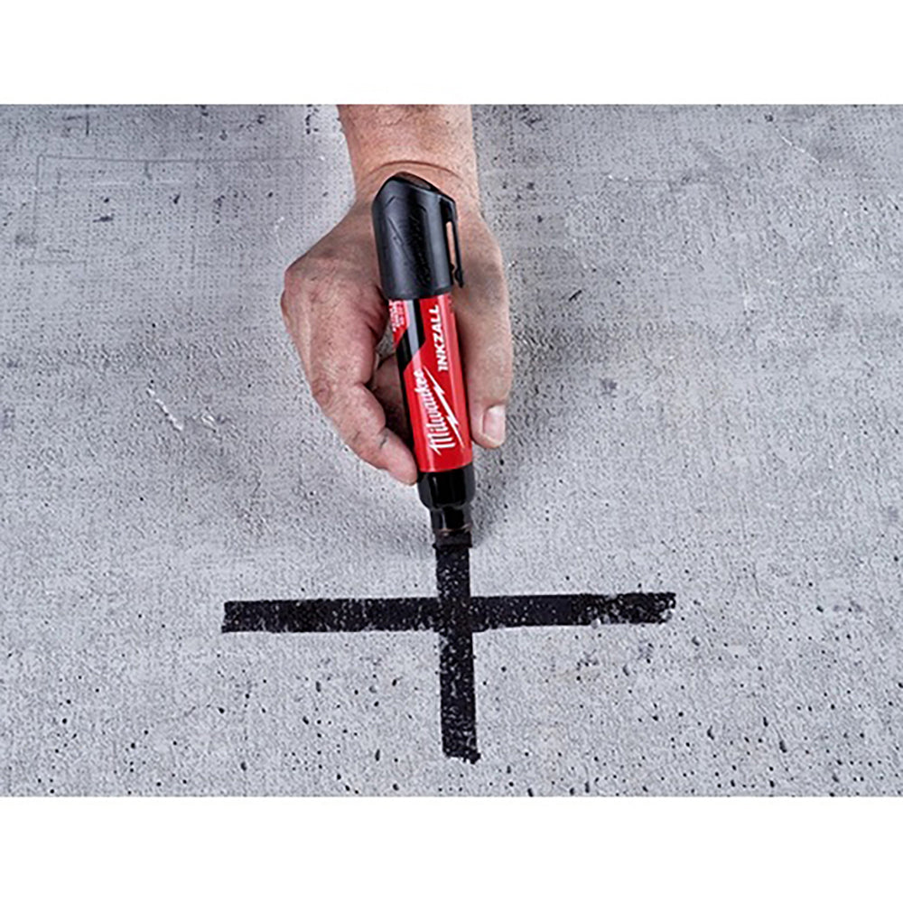 Hand holding a Milwaukee marker on a concrete surface