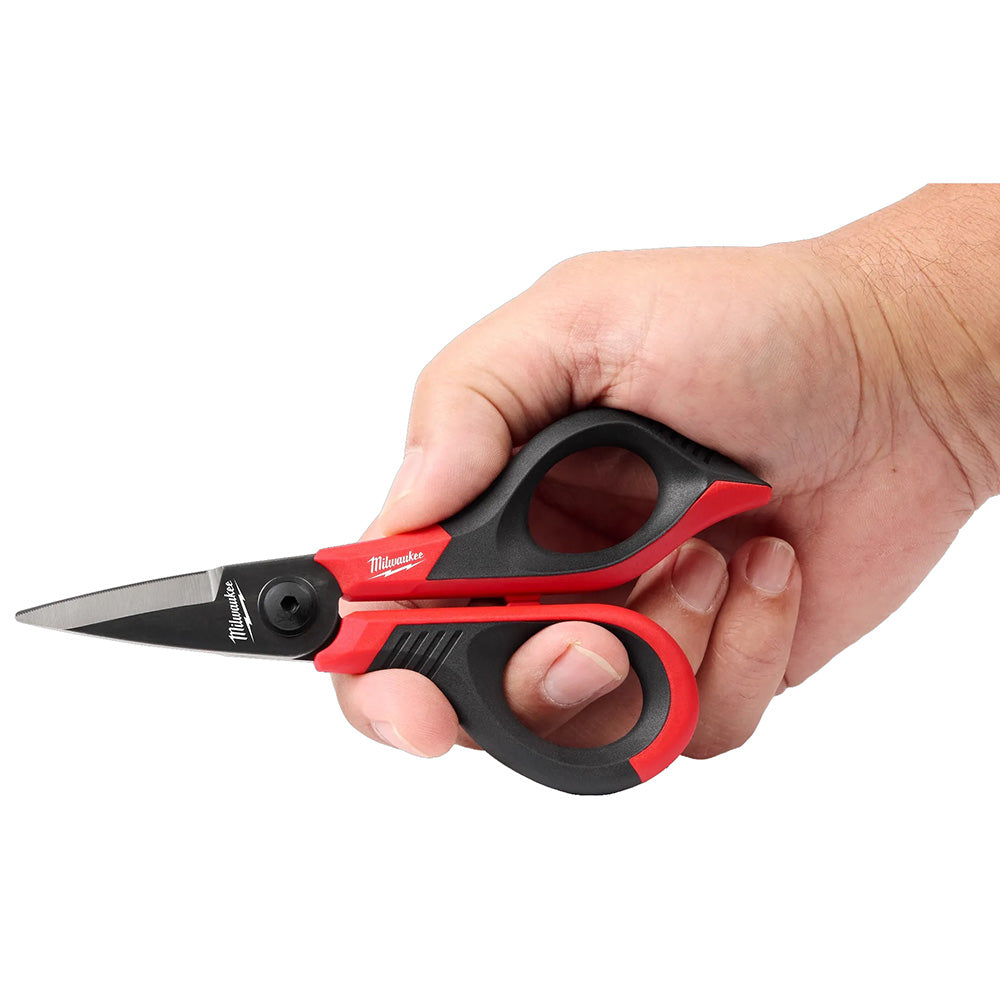 Hand holding a pair of Milwaukee scissors with red and black handles on a white background