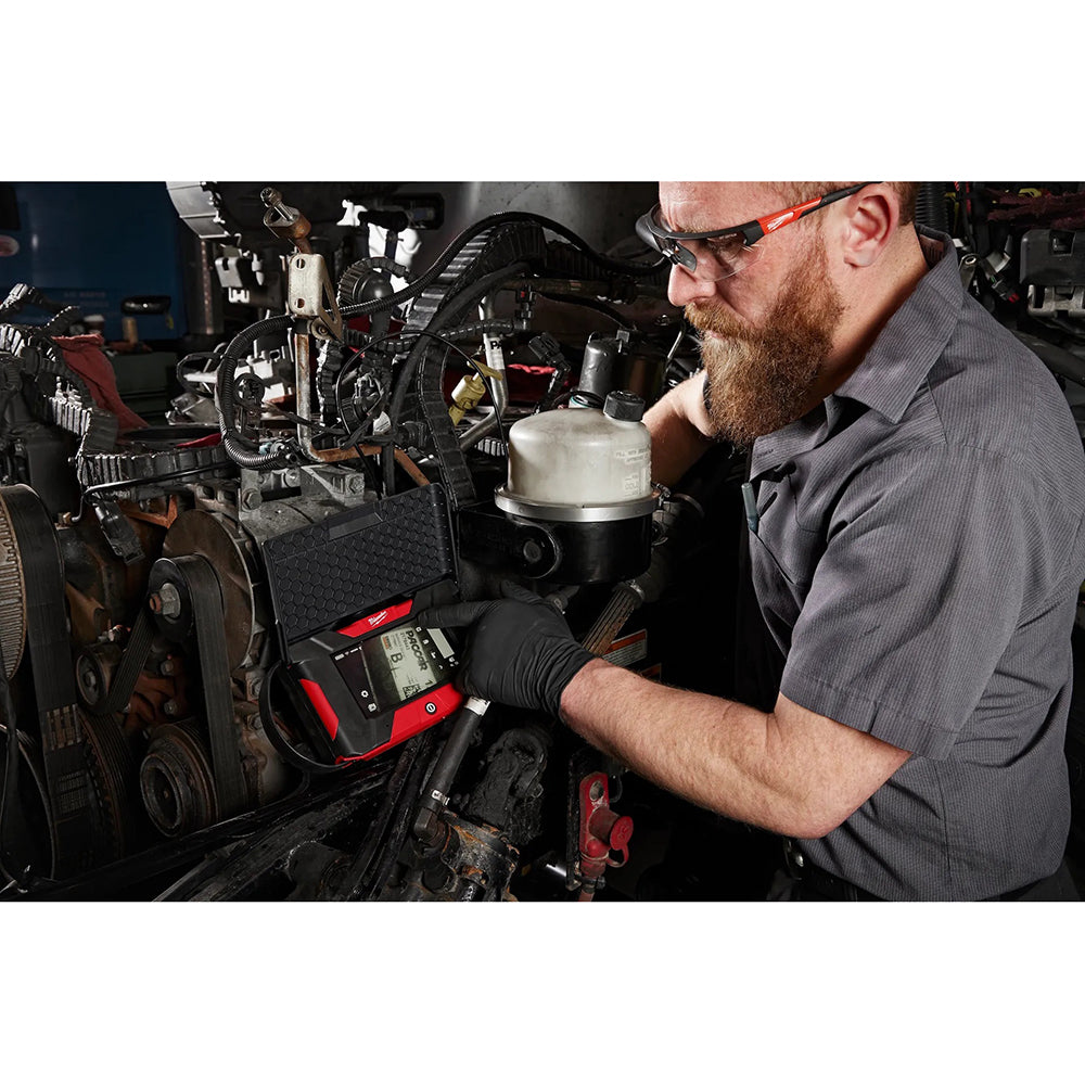 Mechanic working on a vehicle engine with diagnostic tools