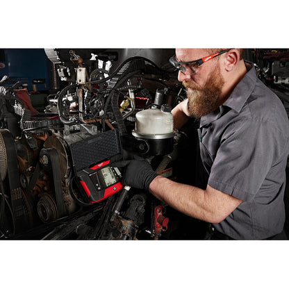 Mechanic working on a vehicle engine with diagnostic tools