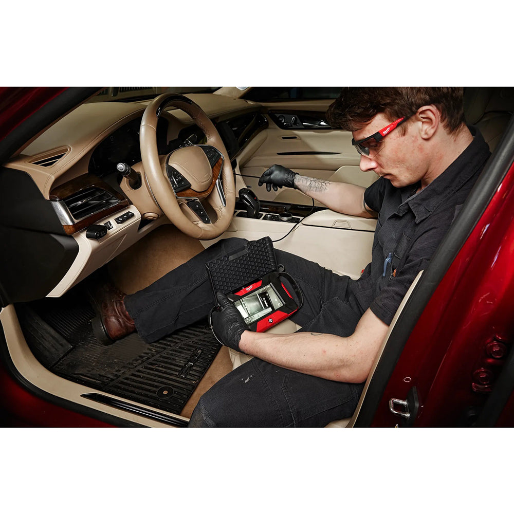Person working on a car interior with tools, wearing gloves and a black shirt.