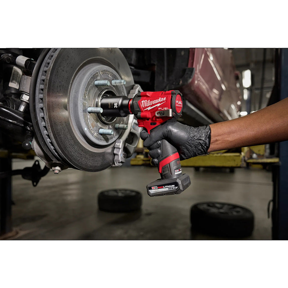 Person using a Milwaukee power tool on a vehicle's brake system