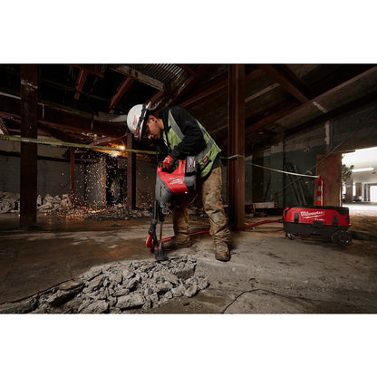 Worker using a Milwaukee tool in a construction setting with debris and equipment.