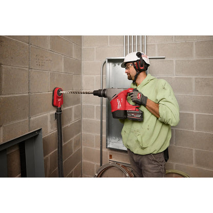 Person using a red power drill in a construction setting with a tiled wall.