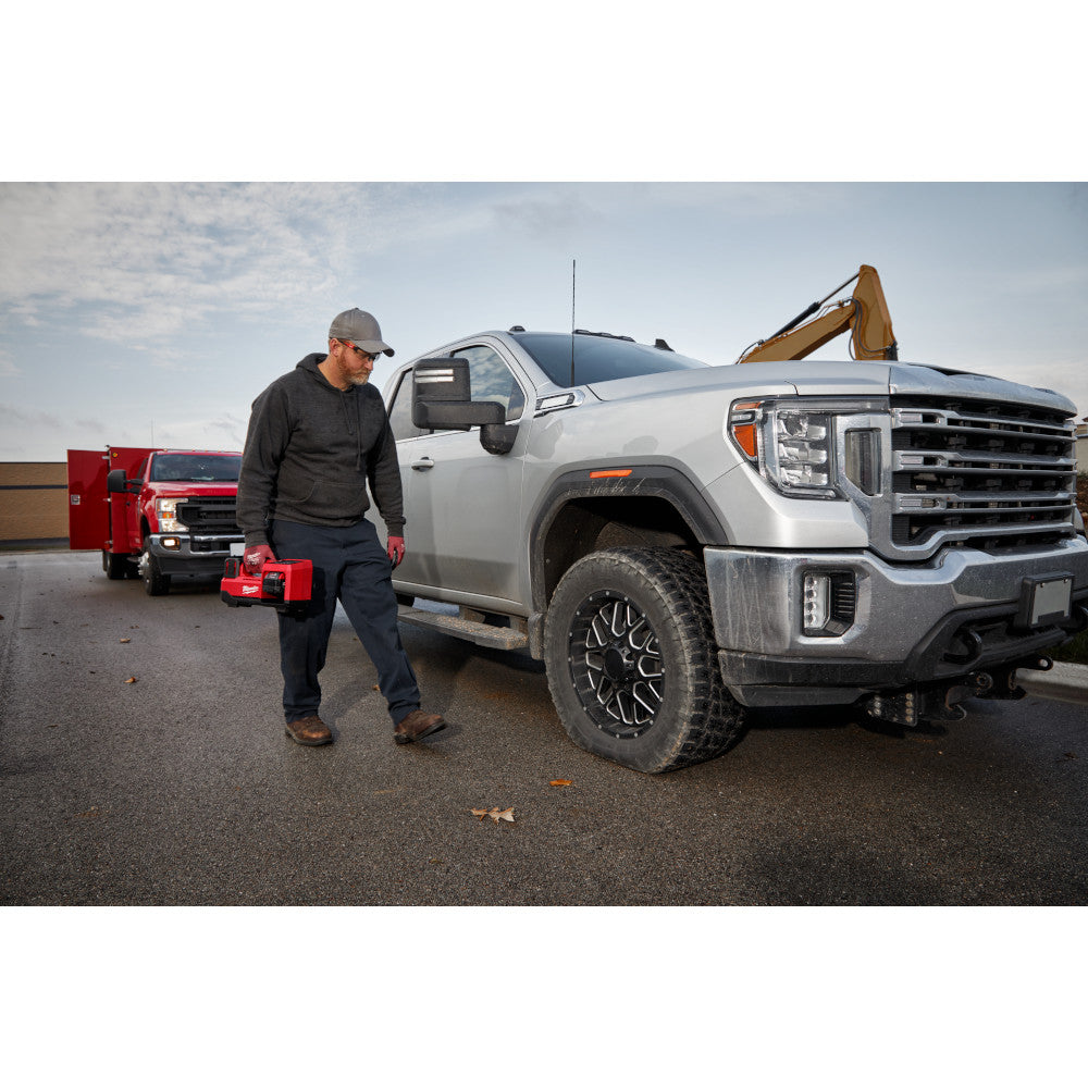 Man with M18™ Inflator standing next to a silver truck in a parking lot.