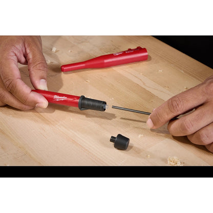 Person assembling a Milwaukee tool on a wooden surface