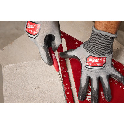 Person using a Pencil with gloves and a ruler on a concrete surface