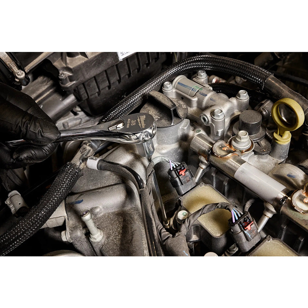 Close-up of a car engine with a wrench being used on mechanical parts.
