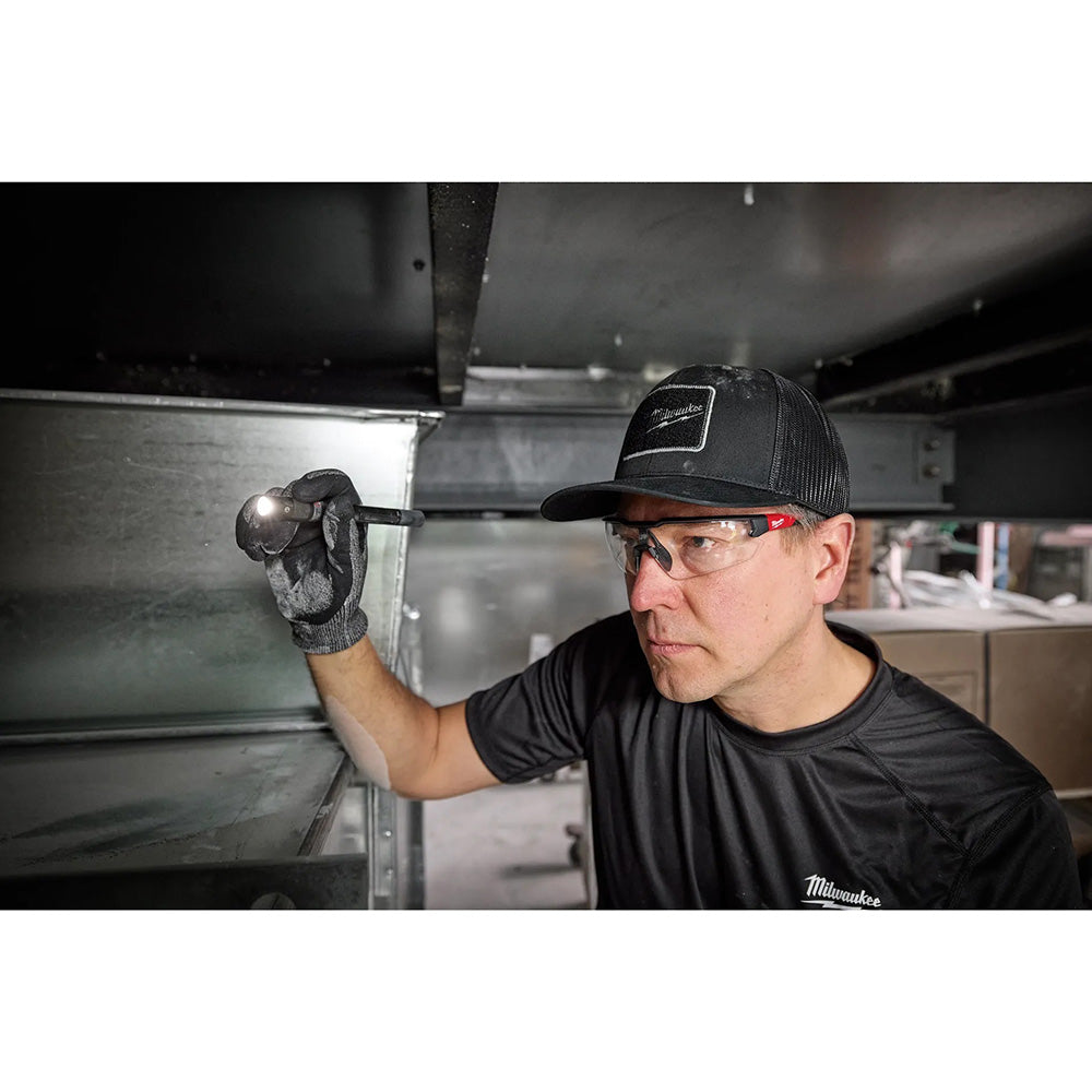 Person wearing a Milwaukee cap and gloves working on a metal structure.